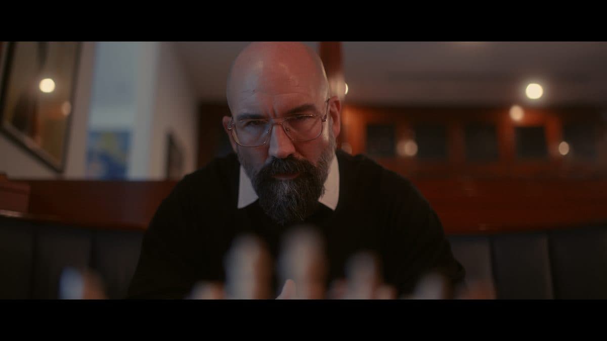 A man reaching across a chessboard in low warm light