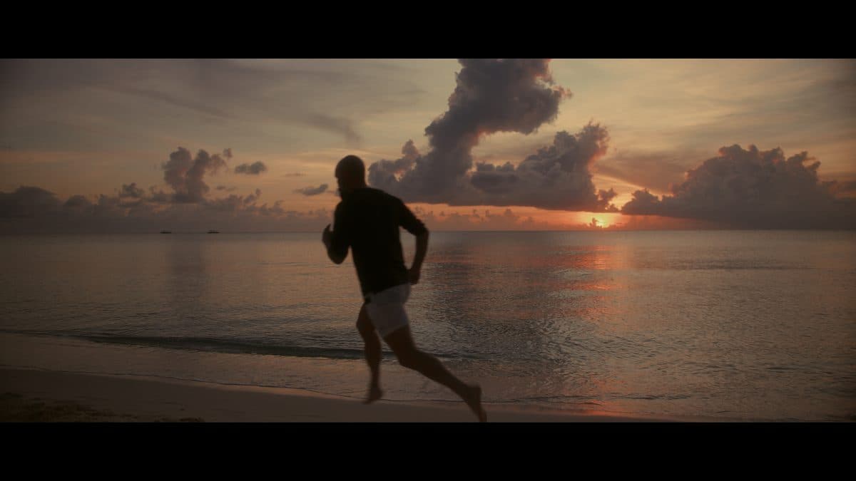 A runner on the beach against a sunrise